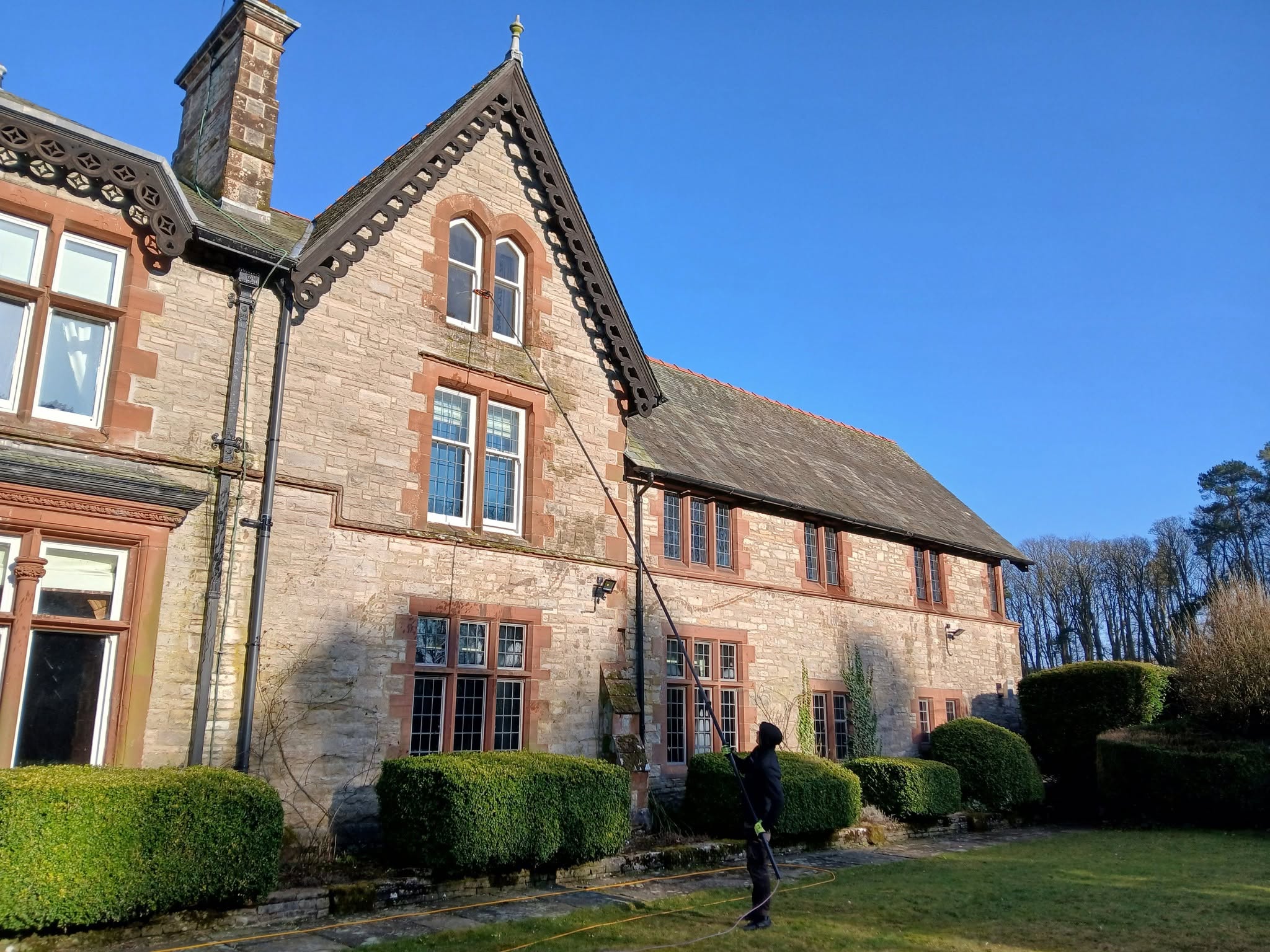 Cleaning the windows of a large Victorian red sandstone house on a bright day