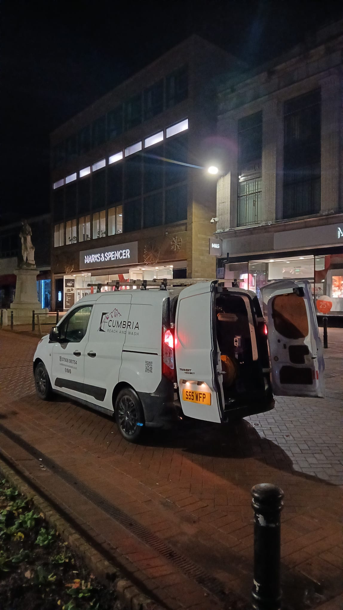 The van parked on a town-centre street in the evening, doors open