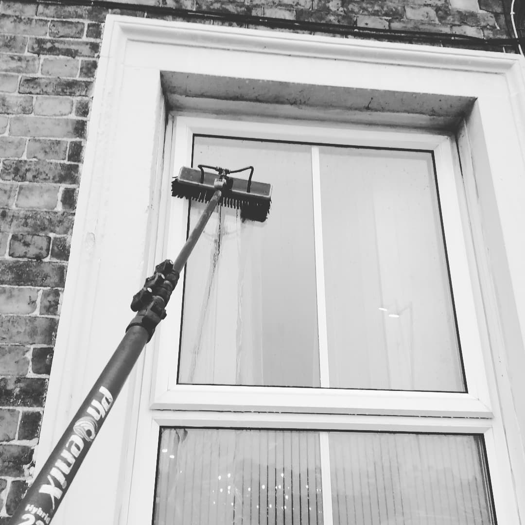 Close-up of a water-fed pole brush cleaning a white uPVC window